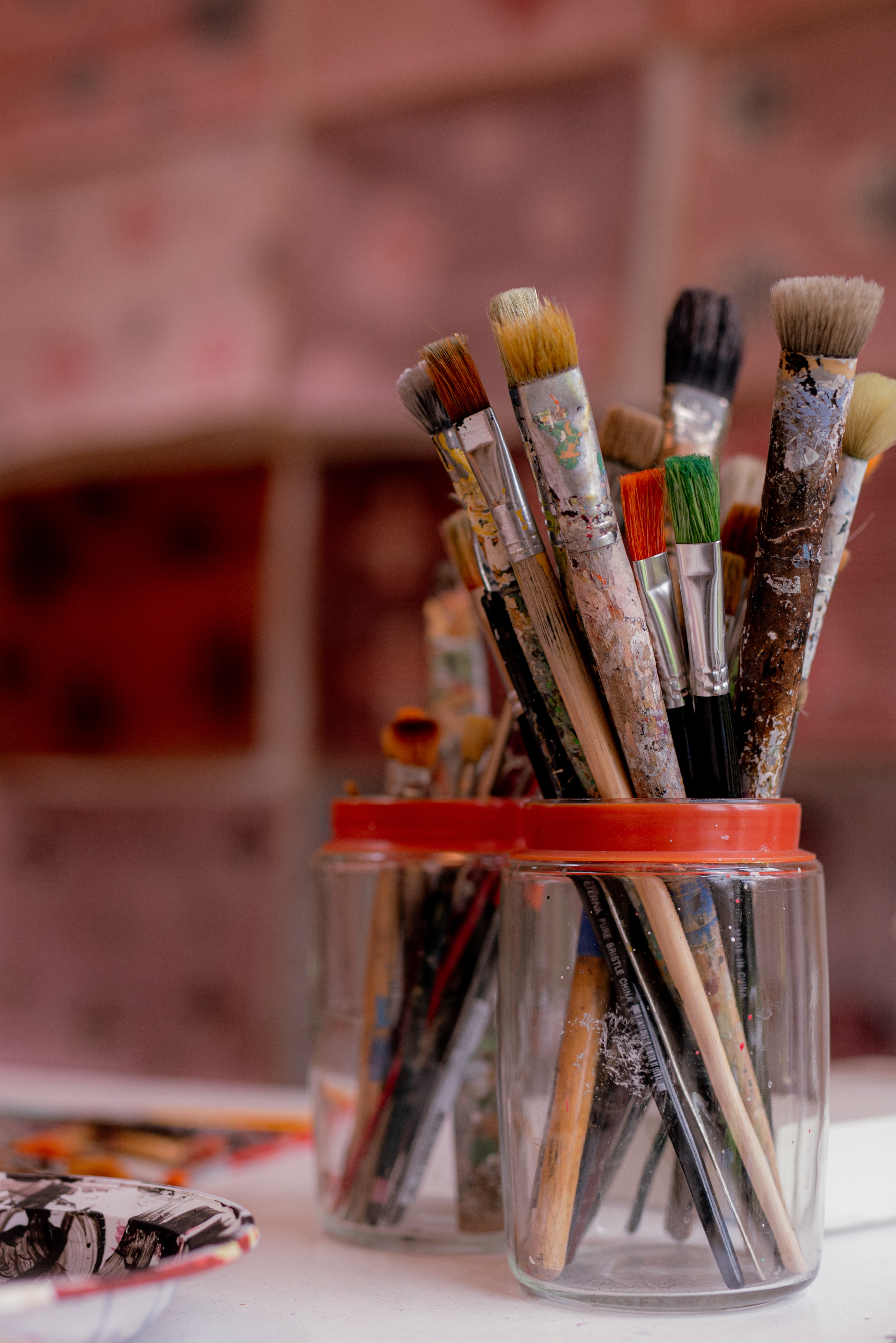 A close up image of used paintbrushes in a glass jar.